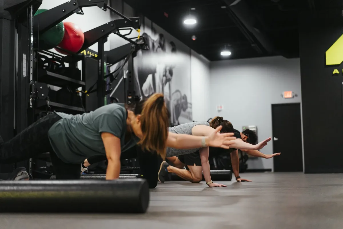 Members at Alloy Personal Training holding a bird-dog balance and stability reach on the studio floor