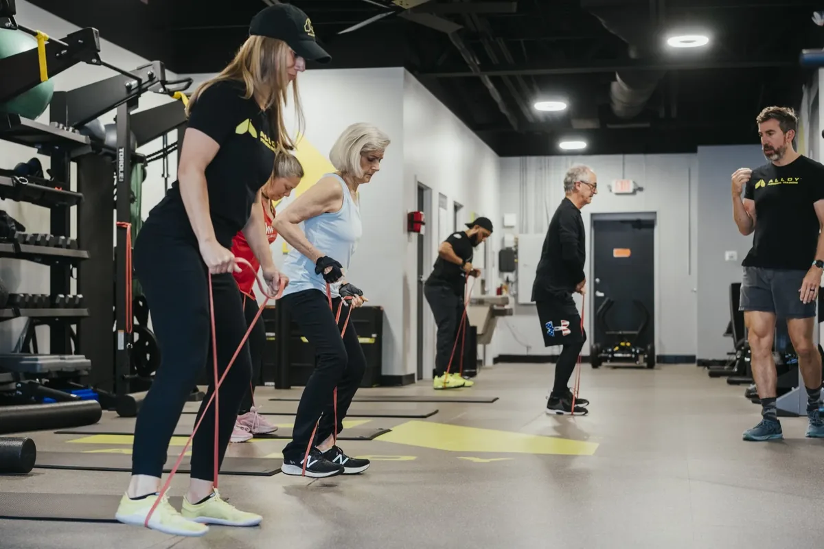 Small group of older adults training with resistance bands, led by coaches at Alloy Madison East
